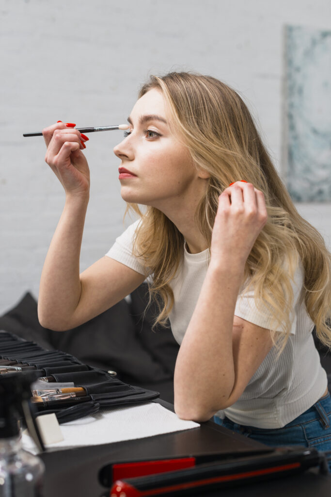 beautiful young woman doing herself makeup sitting studio